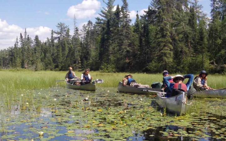 a group of outward bound students rest in their canoes on marsh waters